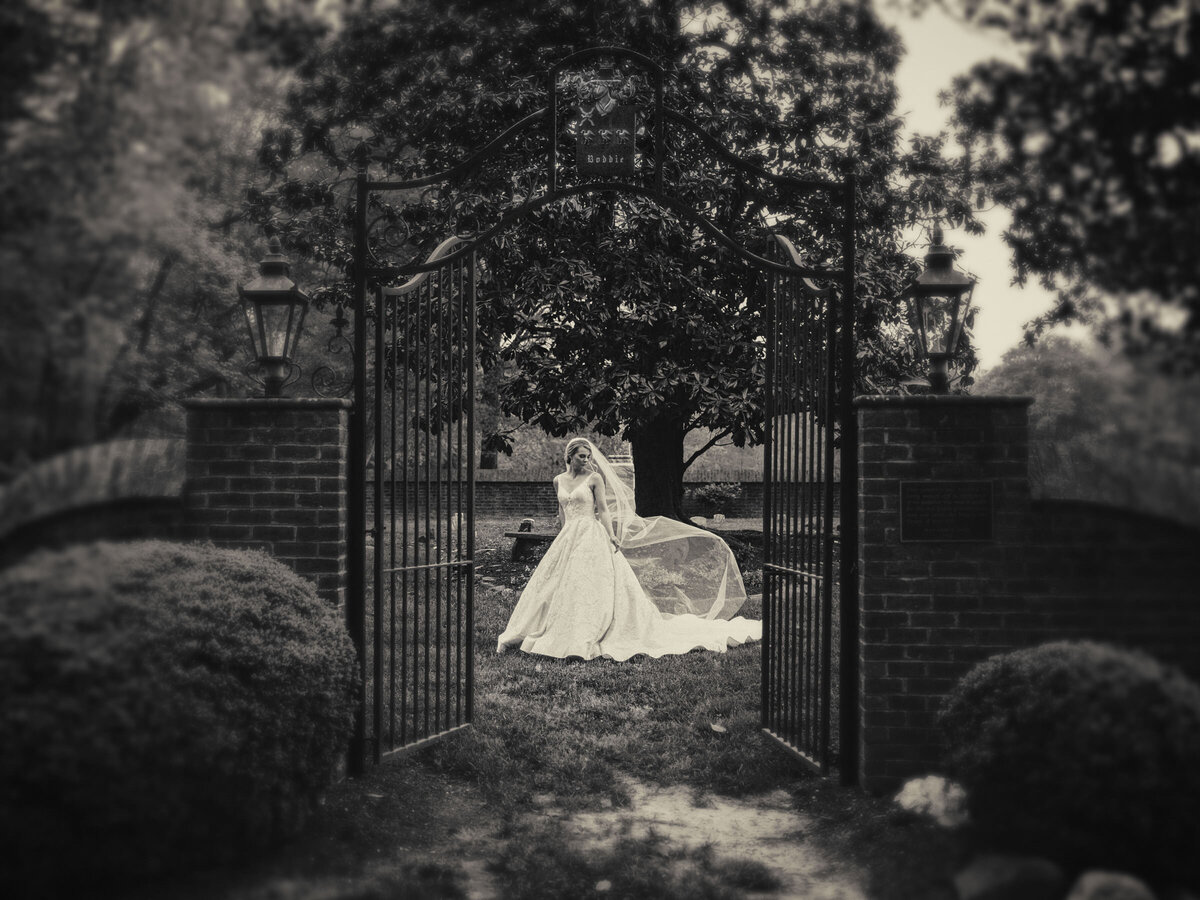 A bride standing outside of a gate on a lawn