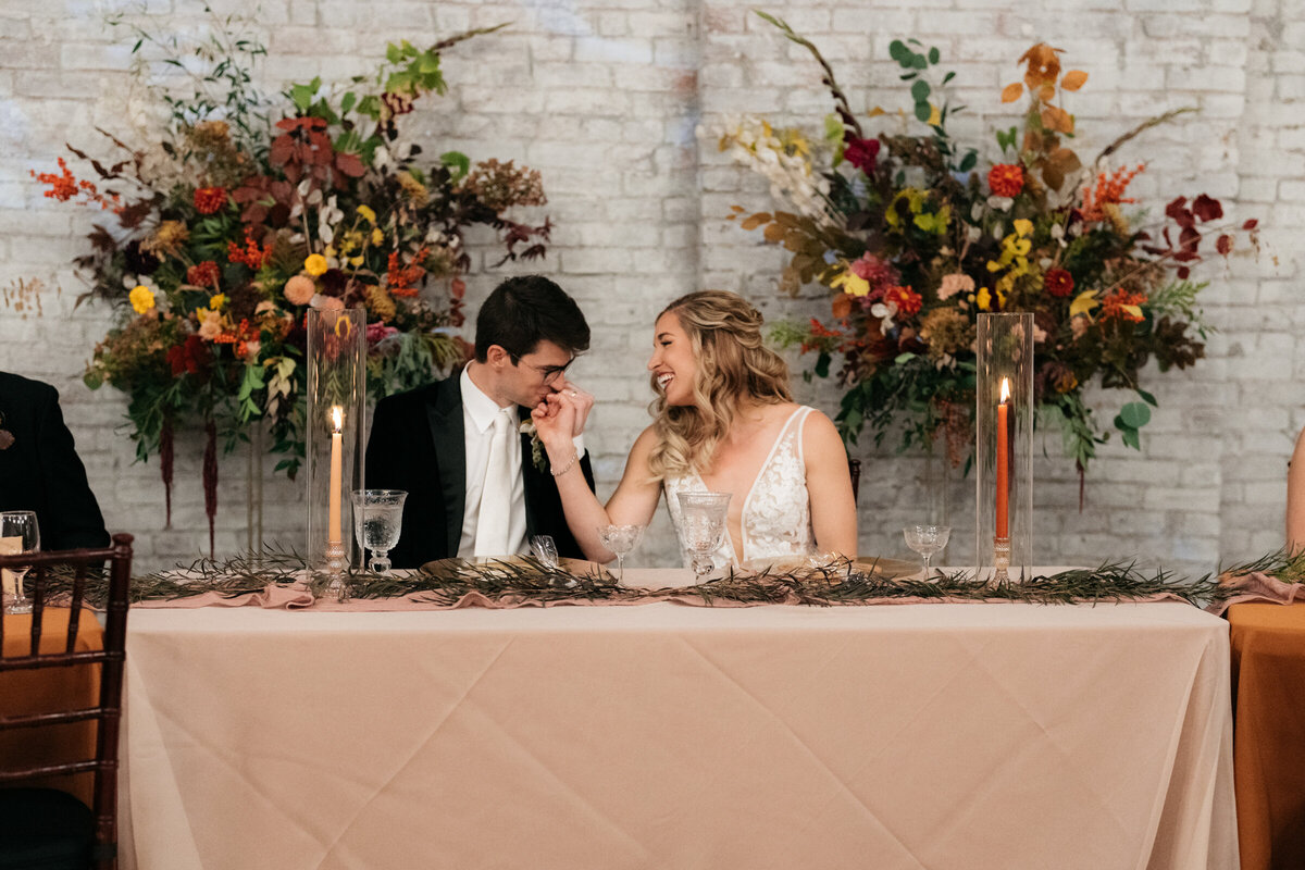 bride and groom sitting at a sweetheart table at the reception