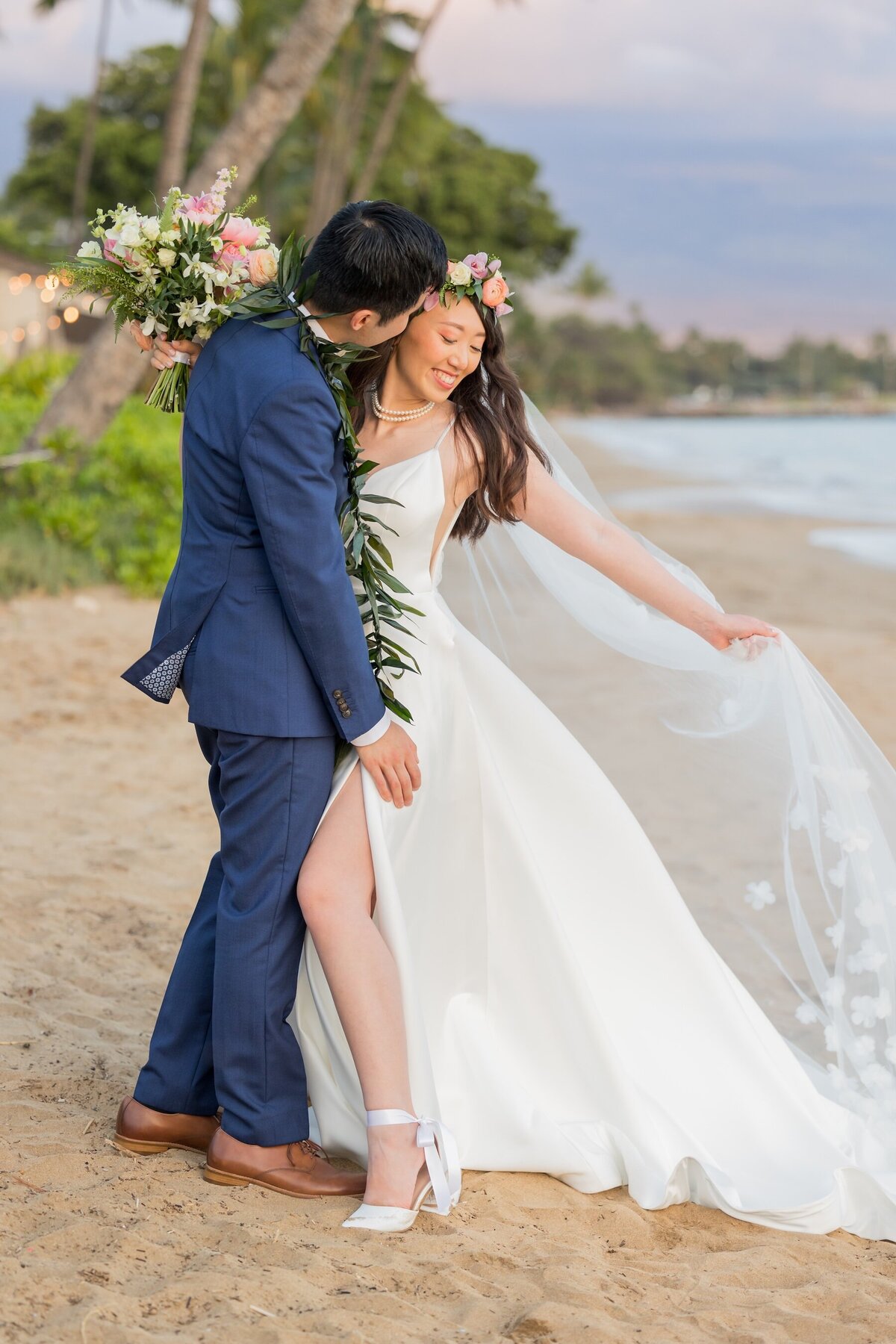 beautiful shot of bride in her dress next to groom on the beach in Maui