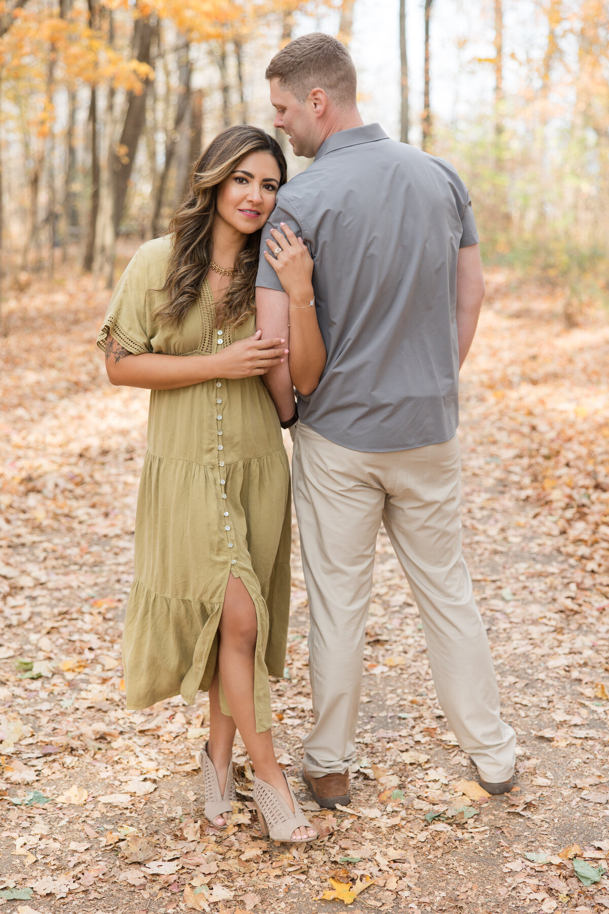 Married couple in which wife is looking at the camera and holding her husband's arm