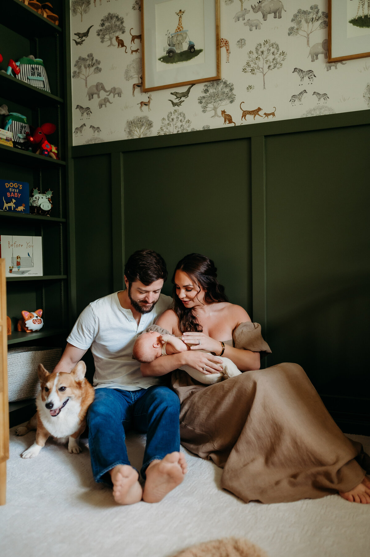 Alternative angle of Artistic image of parents sitting on nursery floor with their baby next to the crib, sitting in beautiful light while holding their sleeping baby in Timonium Maryland
