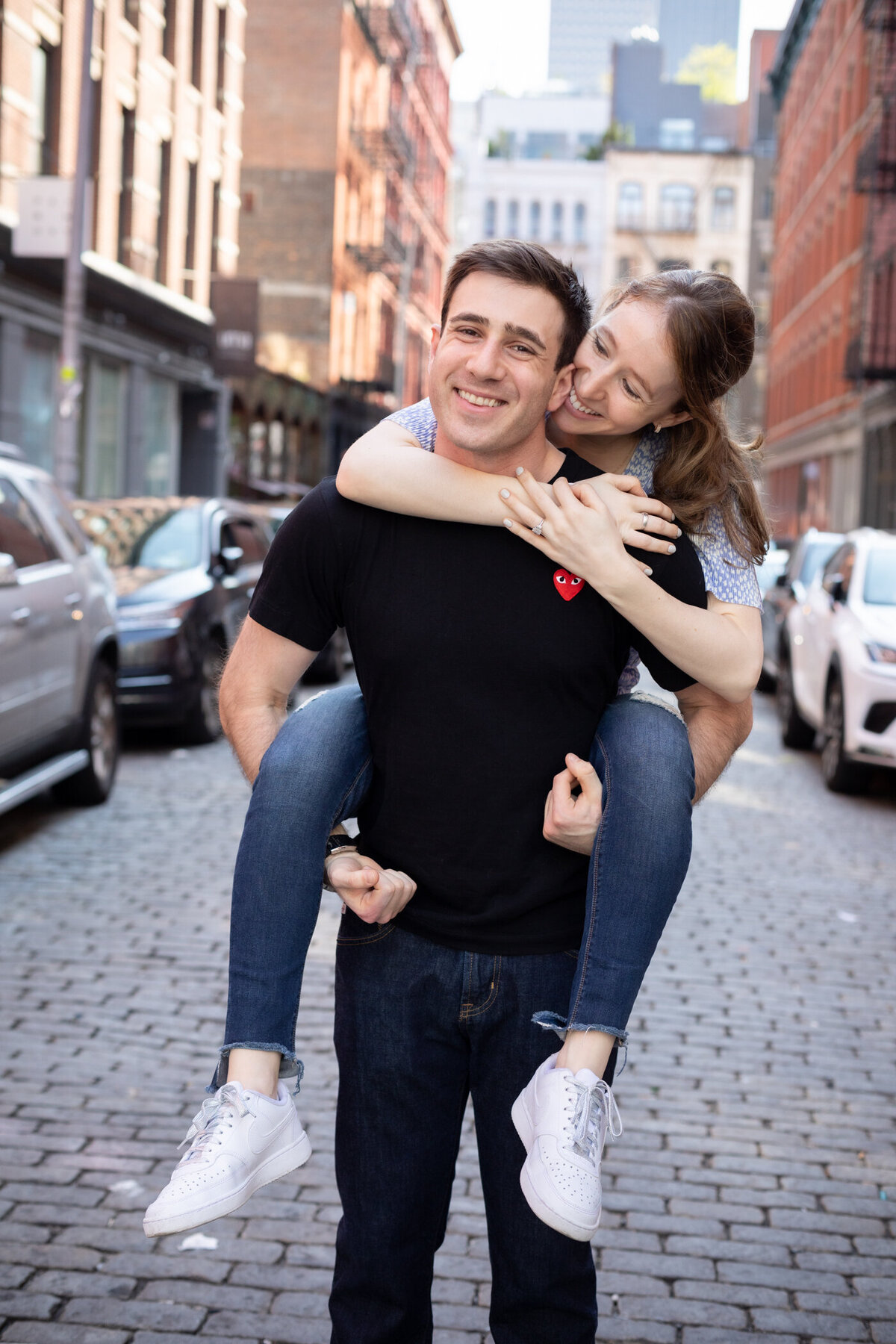 Corey carries Dani on  his back during their playful, soho engagement session