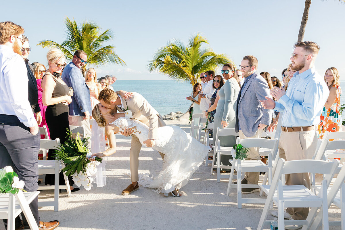 Ashley and Hunter share a kiss as newlyweds while the guests cheer them on.