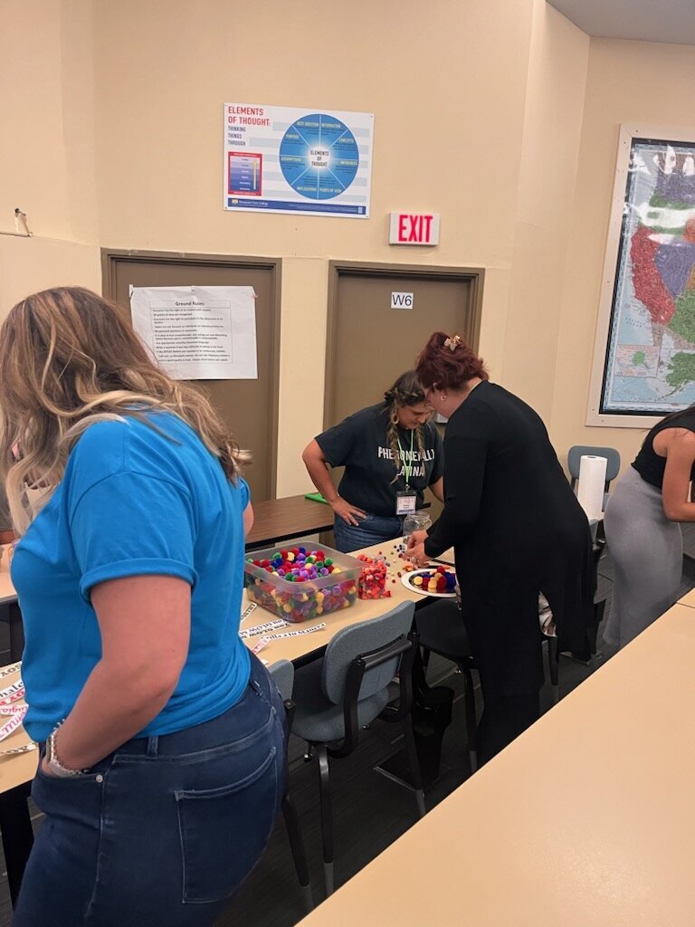 The magic as a group of women gathers around a rectangular wooden table, working collaboratively on crafting a radiant mirror masterpiece.