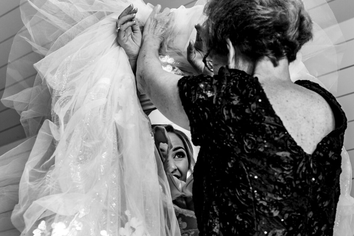 Mom helps bride get into her wedding dress