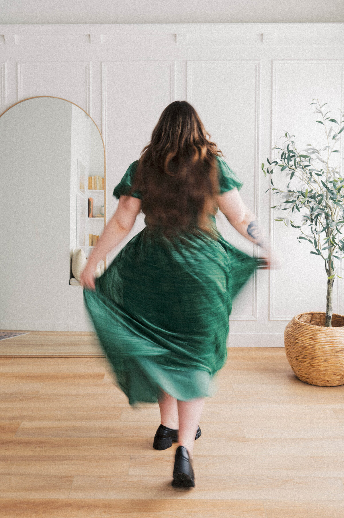 Blurry image of woman wearing green dress walking away towards while wall