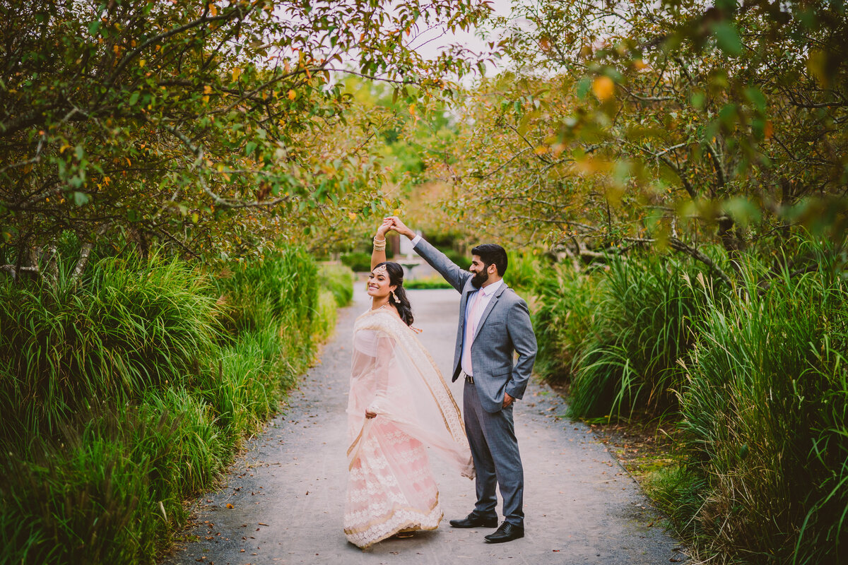 Groom twirling the bride in indian sari inside the walled garden at caumsett state park during their engagement session