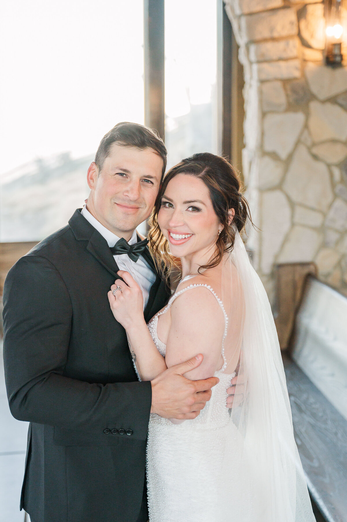 A happy couple embracing in front of warm church pews at The Cliffs at Glassy Chapel by destination wedding photographer, JoLynn Photography