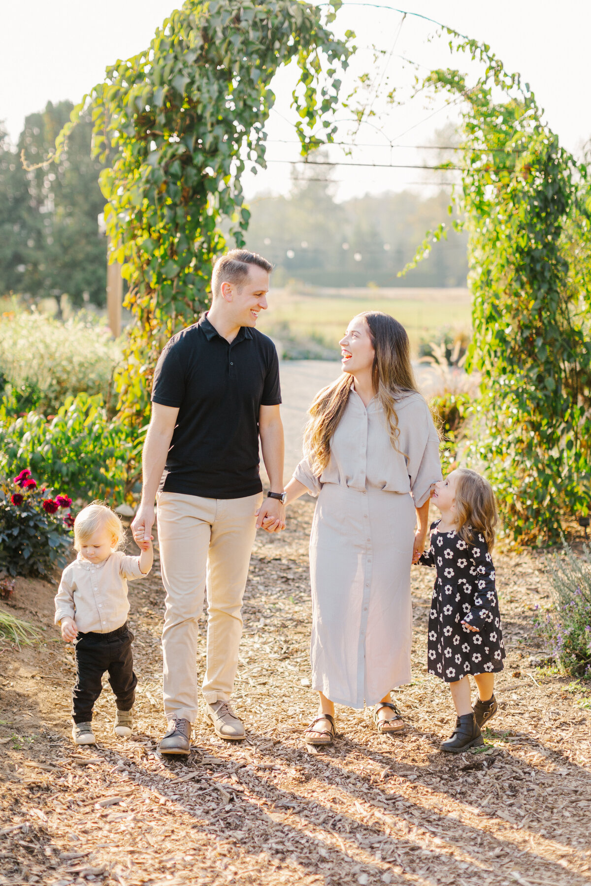 Family of four holding hands and walking while smiling at each other