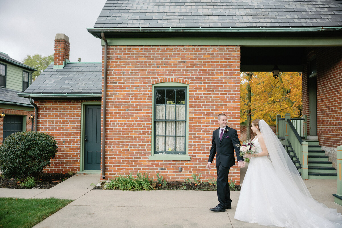 bride and groom walking in front of brick building