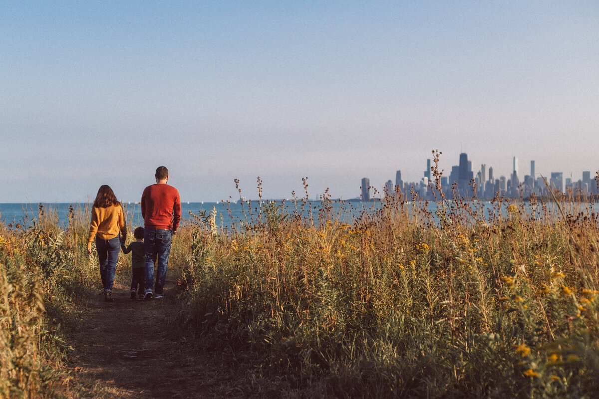 Family walking towards Chicago skyline during lifestyle family photoshoot.