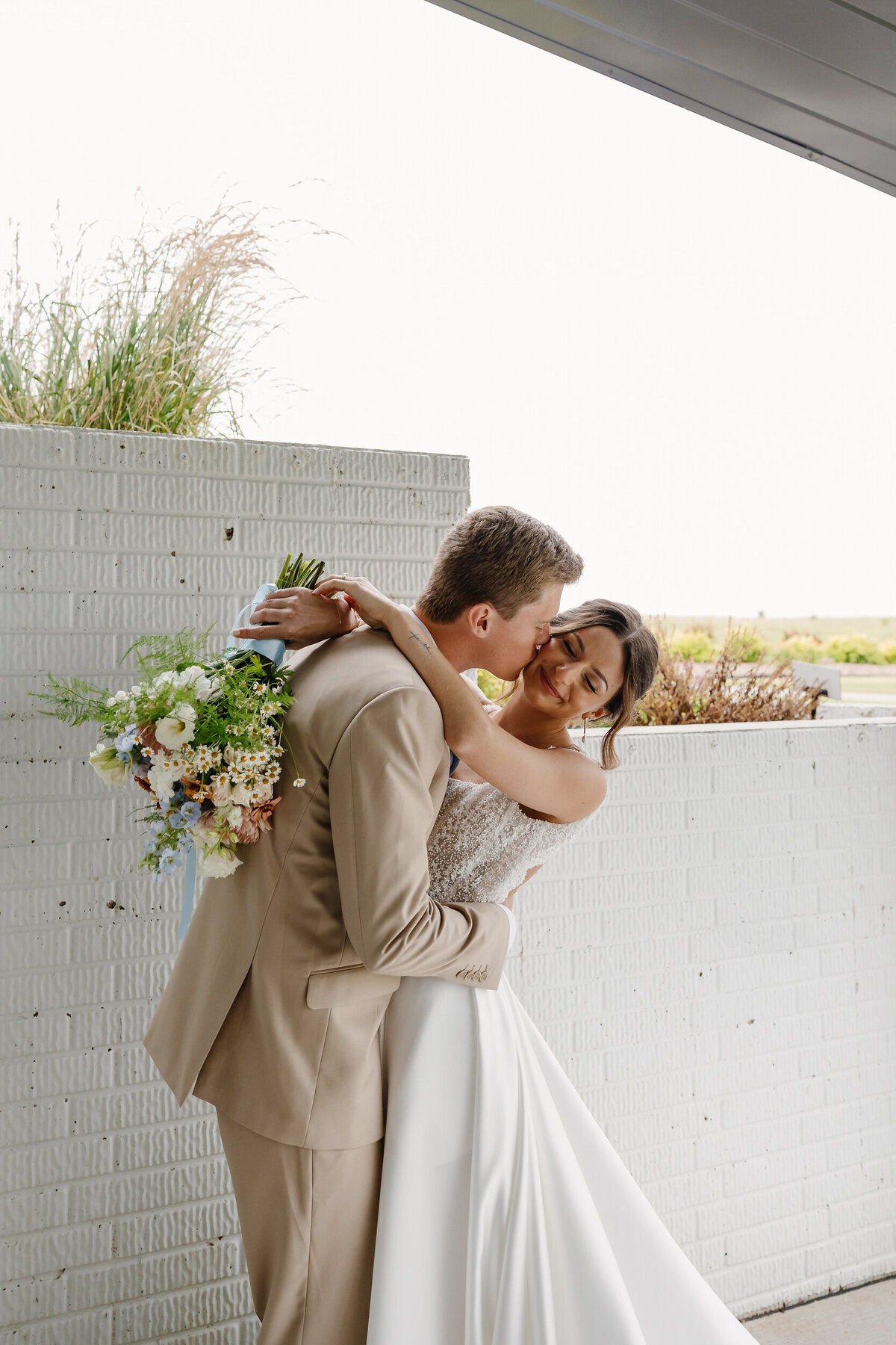 A person kissing their partner's cheek on their wedding day