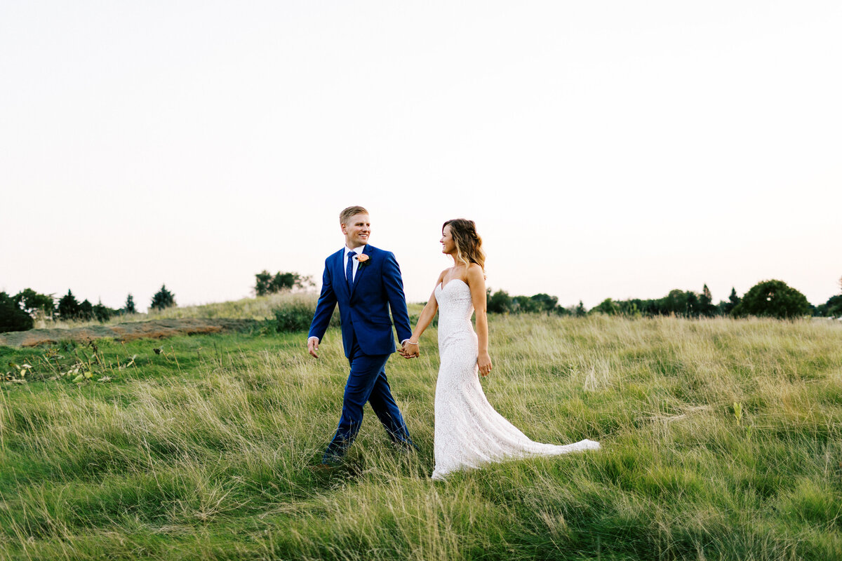 bride and groom walking in the field with  joy holding hands in Minnesota