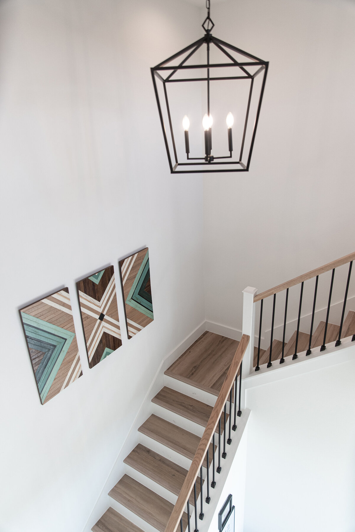 wood staircase with black railing and farmhouse light