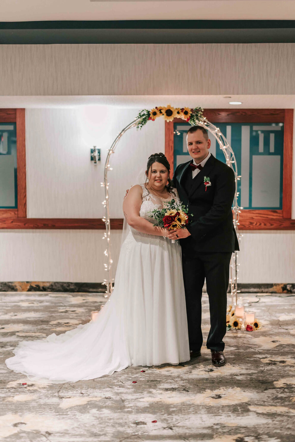 Bride and groom standing together in front of their wedding arch.