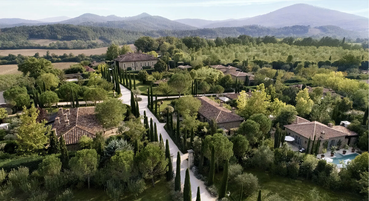 Bird's eye view of Borgo Santo Pietro, a refined Italian country borgo with classic stone buildings spread out between cypress ree lanes, gardens and forests
