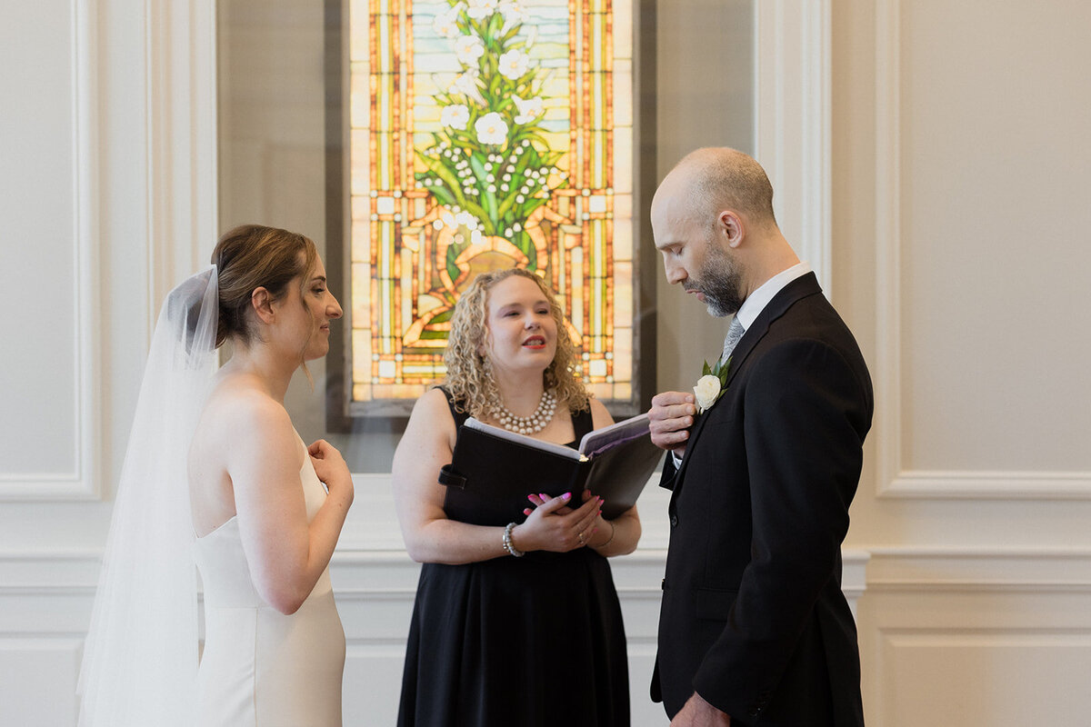 The couple holds the rings to their hearts as the ceremony officiant speaks to them.
