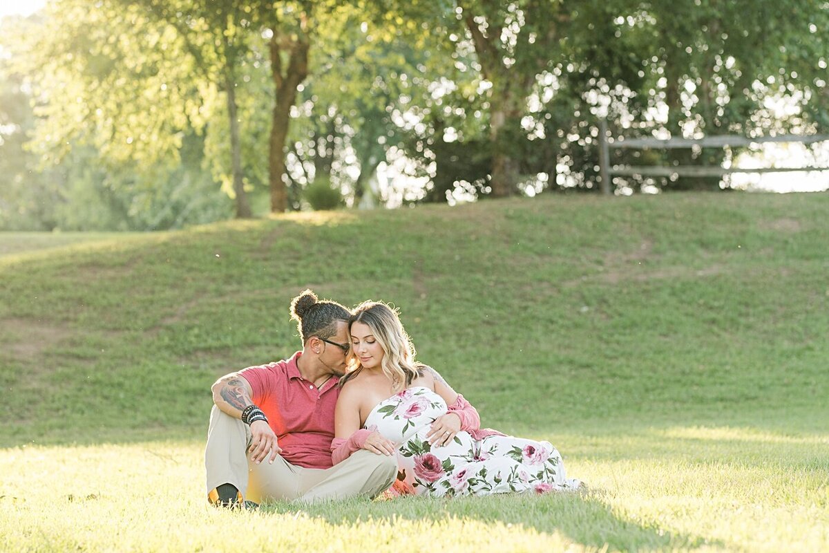 new parents to be sitting opn ground cuddling during their maternity photo shoot in hickory nc