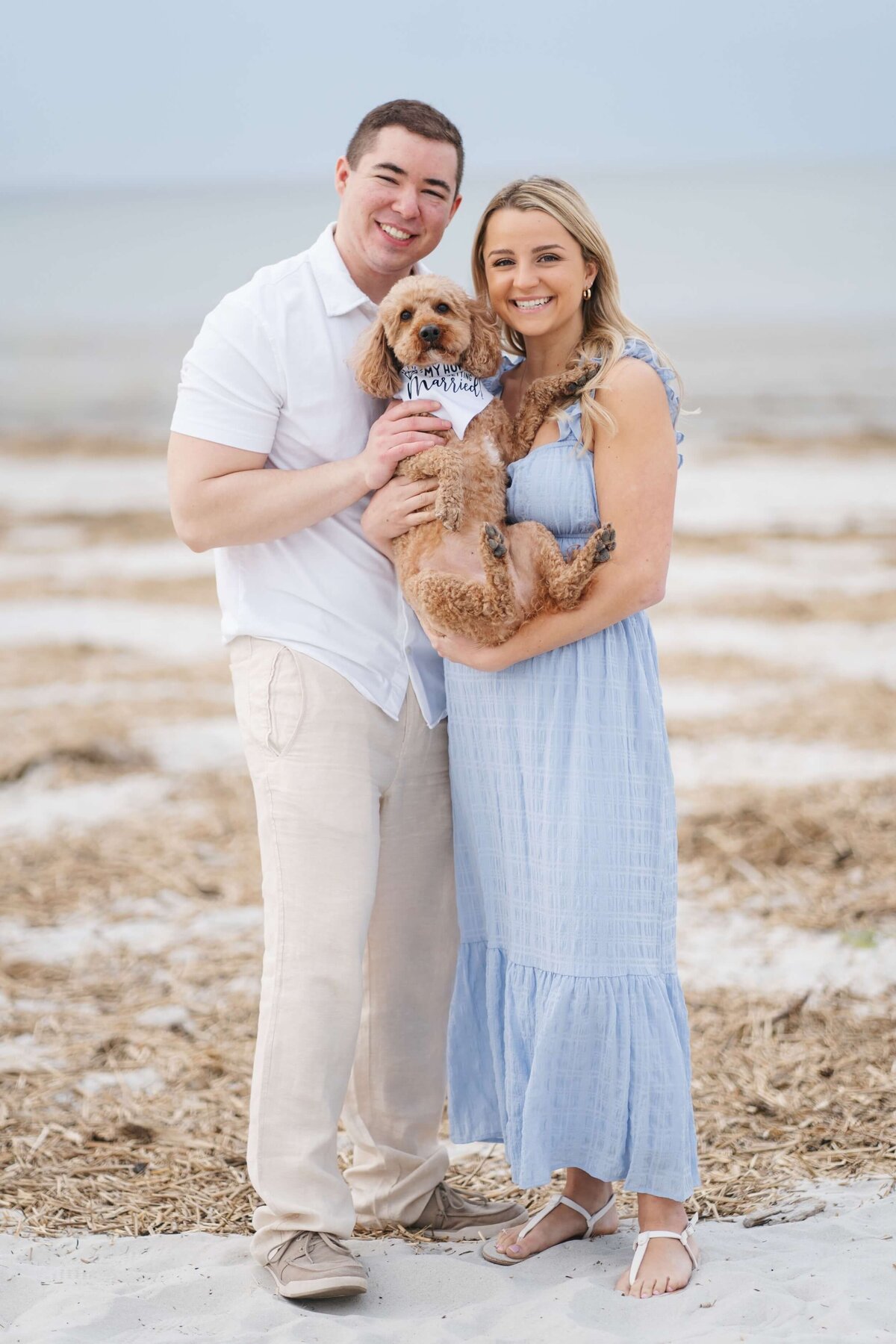 couple getting engagement photos at Wingersheek beach holding their dog
