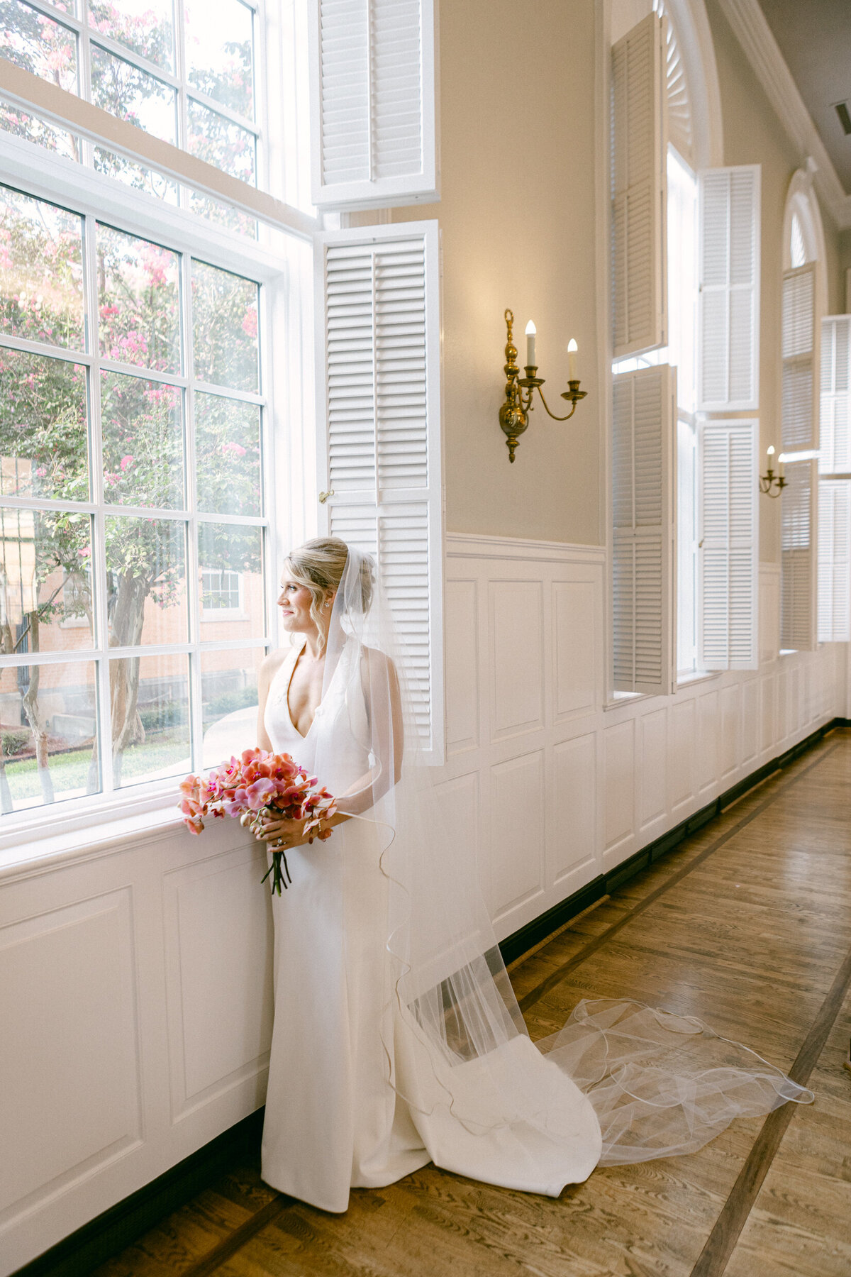 A wedding day portrait photo of the bride looking out a window in the church