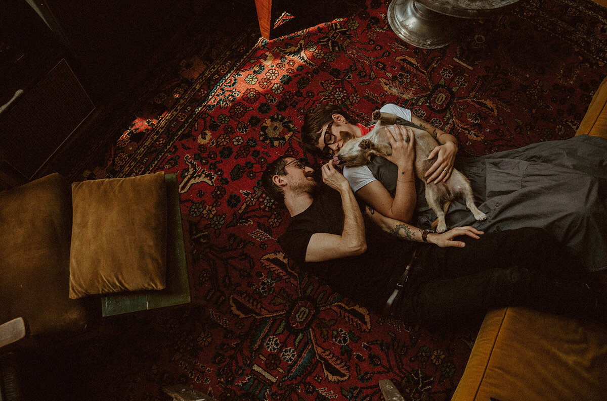 married couple lays on floor of their funky apartment in Boston with their dog 