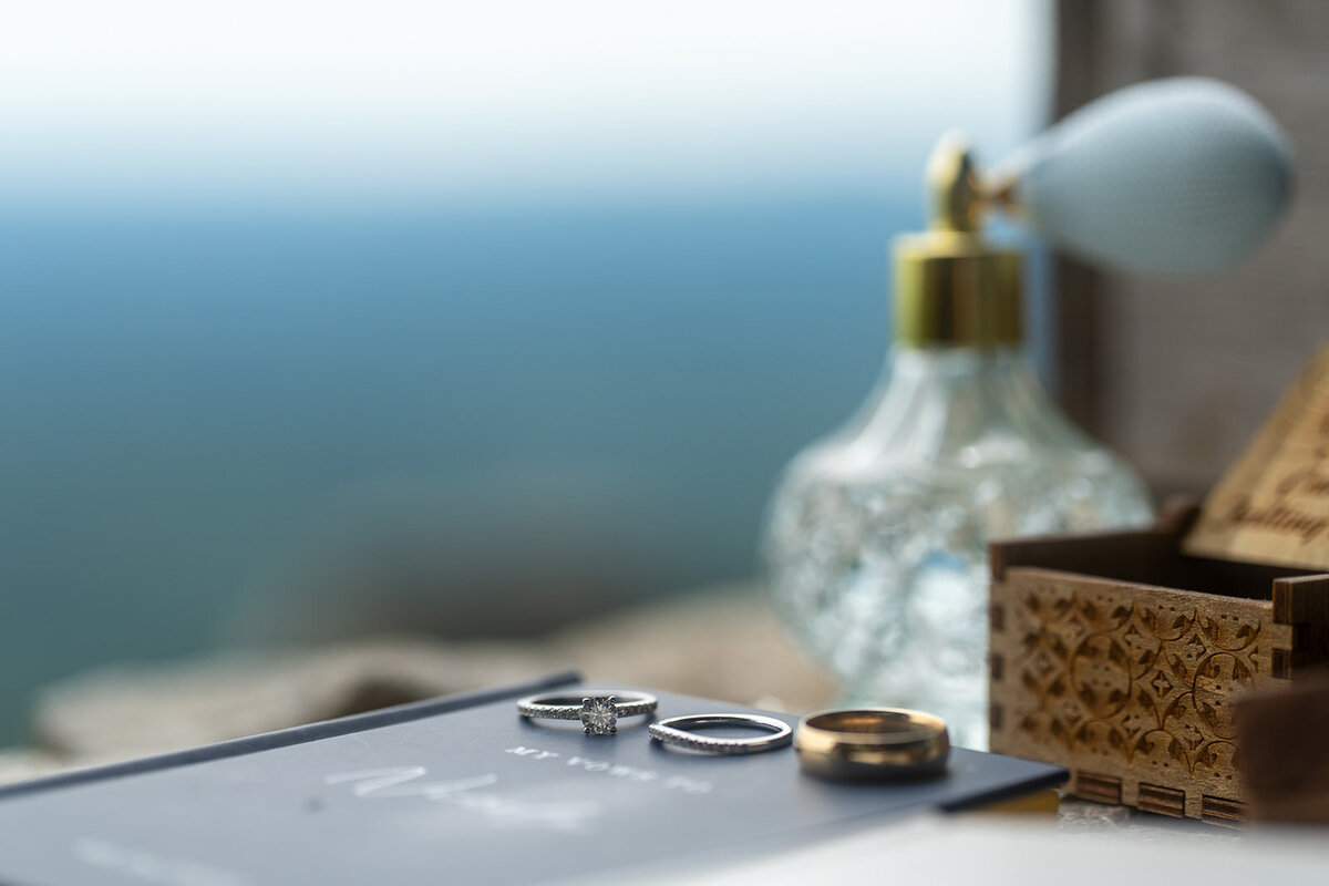 Perfume and rings on a rock with a mountain view background
