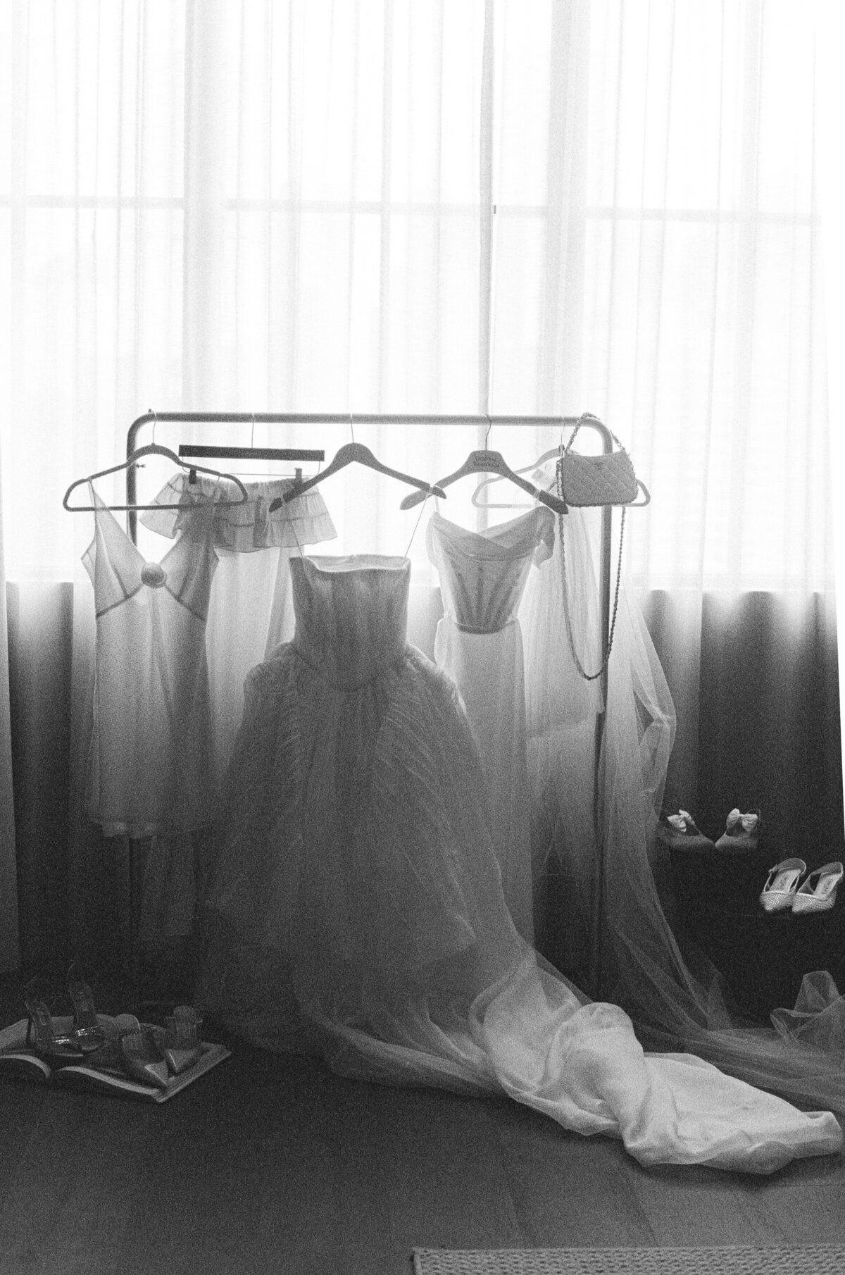 Fashion forward bridal preparation at NOBU Hotel Chicago featuring elegant wedding dress and lingerie on vintage garment rack, captured in timeless black and white film photography showcasing Lauren Alatriste's editorial wedding style.