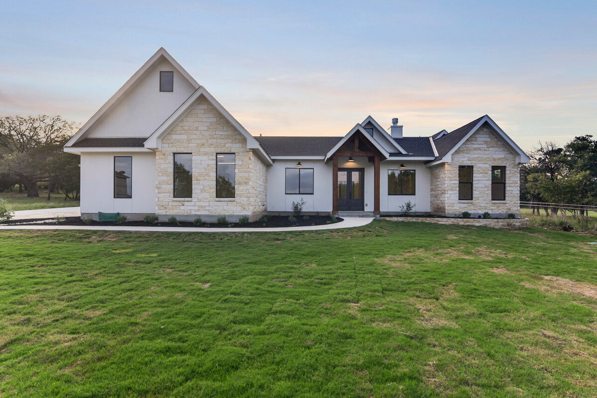 limestone and stucco texas hill country house with black windows