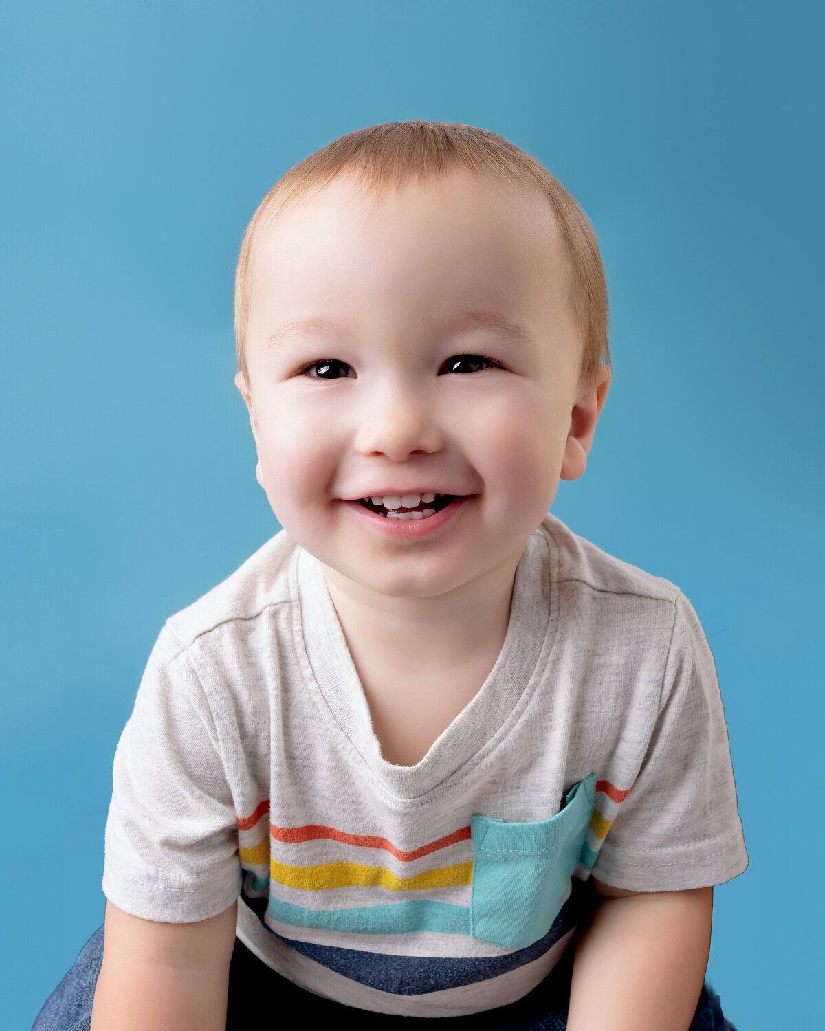 Toddler in a striped shirt on a blue background.