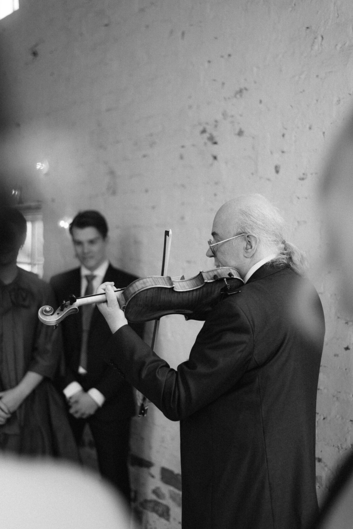 Valokuva viulistista vihkimisessä Oitbackan kartanolla hääkuvaaja Hannika Gabrielssonin kuvaamassa dokumentaarisessa hääkuvassa.