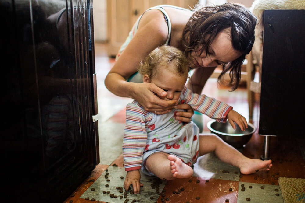 mother catches child eating the dog food on the floor
