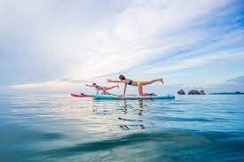 Women doing yoga on paddle on the ocean