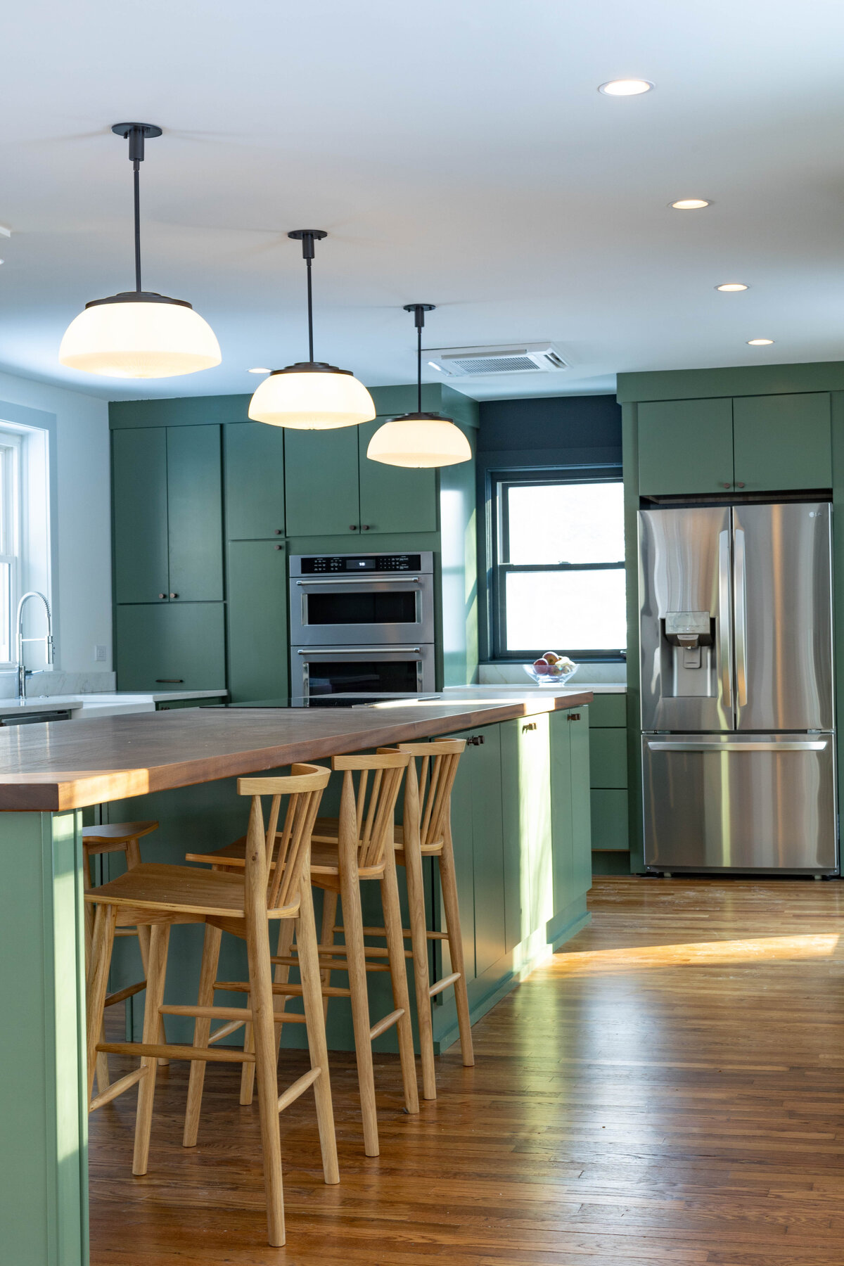 moden kitchen with green cabinets and wooden stools