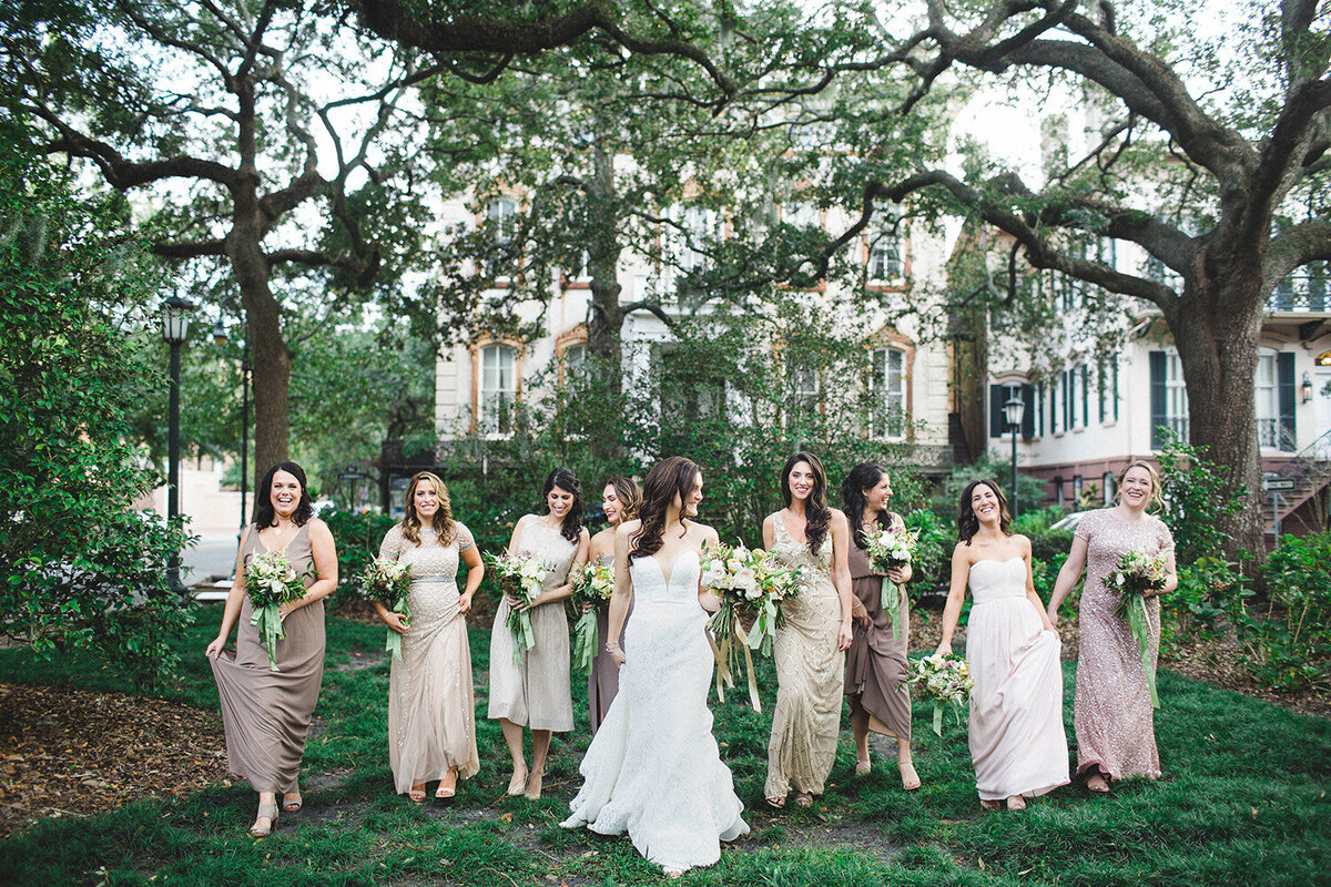 Bride standing with bridesmaids in meadow.