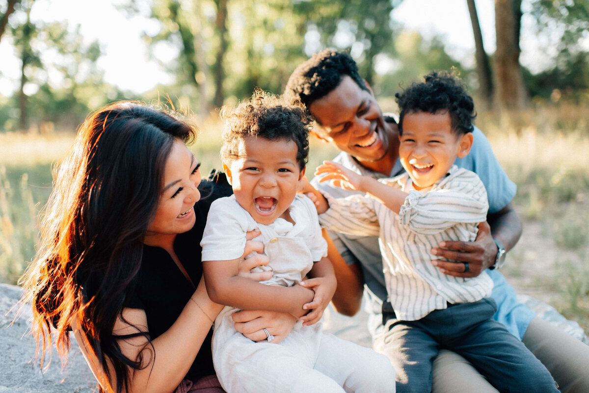 family of four with two young boys laughing together