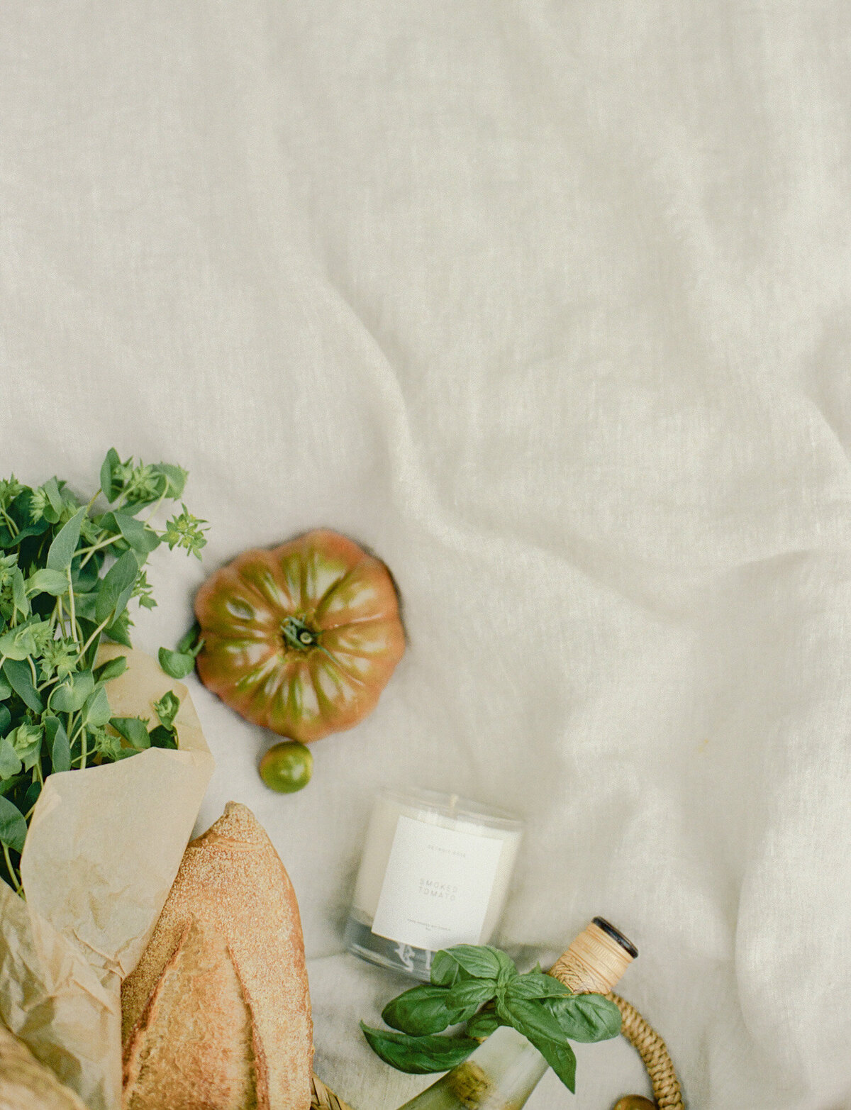 candle product photography, artistic, conceptual film branding photo for candle company, beige linen, picnic, heirloom tomato