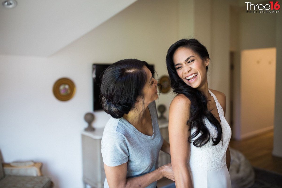 Bride sharing a laugh while getting dressed