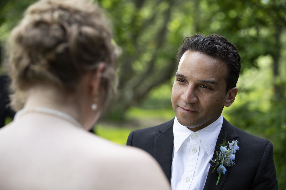 Groom looking into his brides eyes during wedding ceremony Tyler Arboretum in Pennsylvania