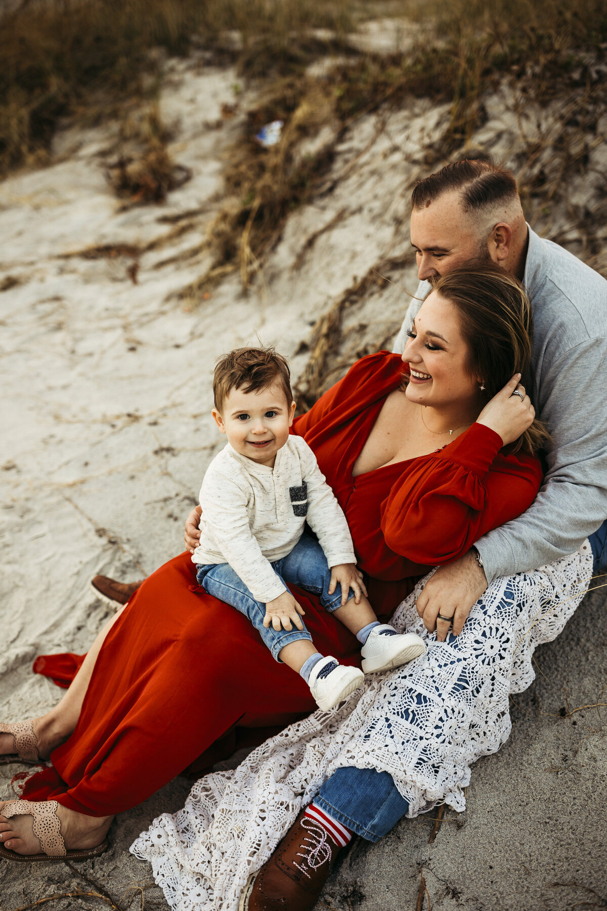 Joyful family on beach smiling baby mom in dark burnt orange dress