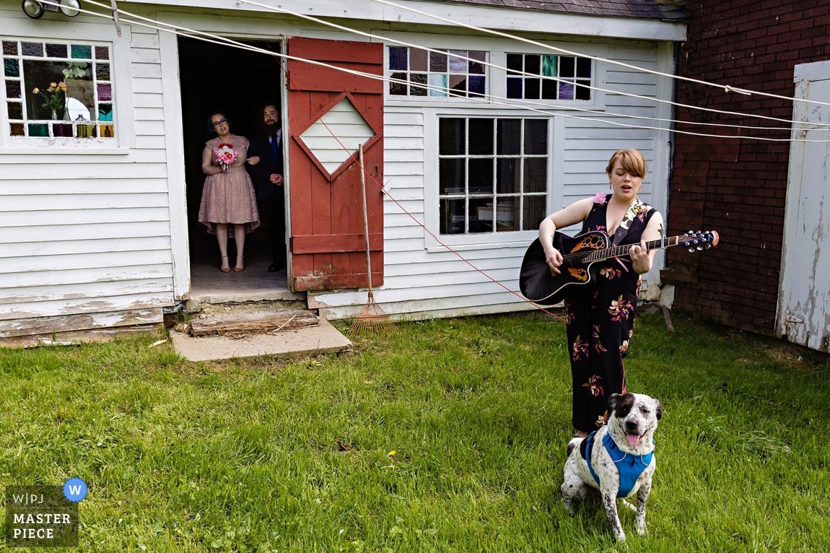 Barn wedding in Maine with the friend singing the wedding party into the ceremony