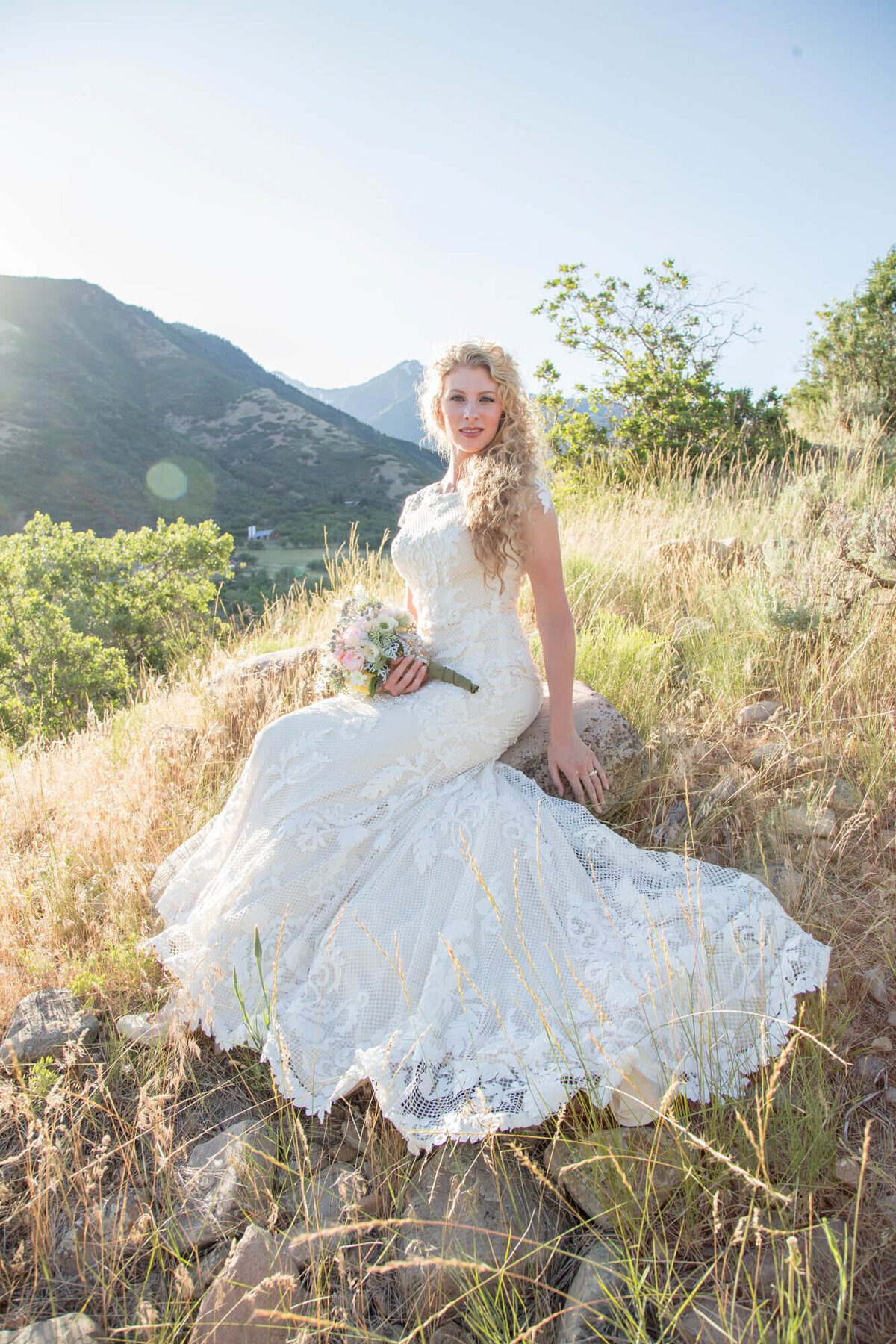 a bride sitting on a rock with a bouquet