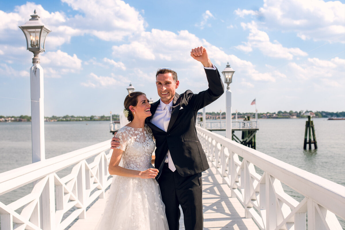 A bride and groom standing on a pier.
