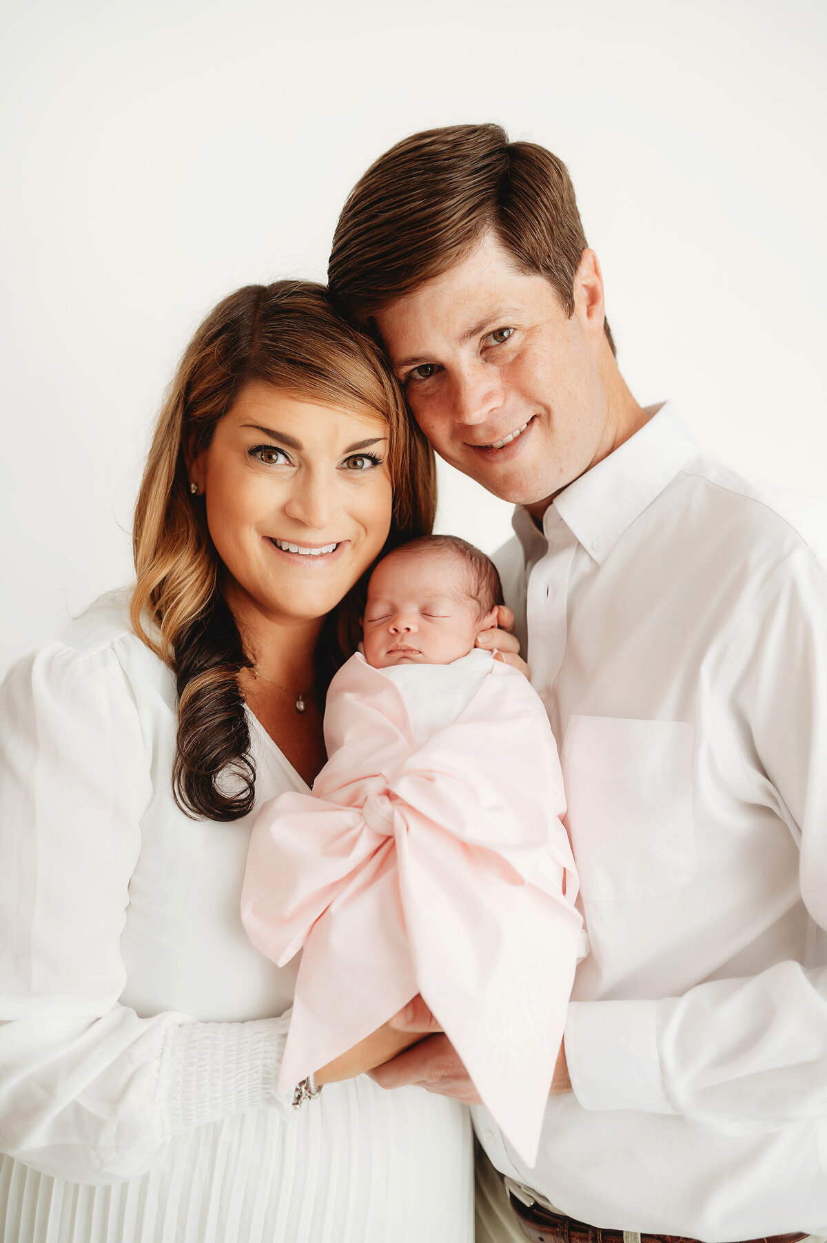 Parents pose with their newborn baby during portrait session at Asheville Newborn Photography Studio.