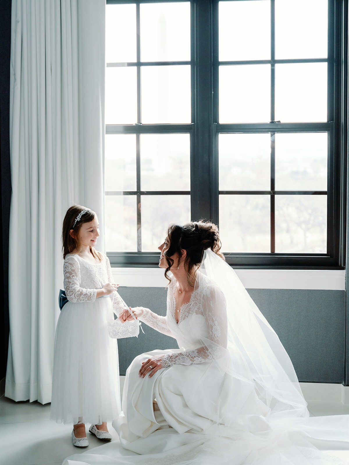 Bride shares a moment with flower girl by window at the Hotel Washington in DC