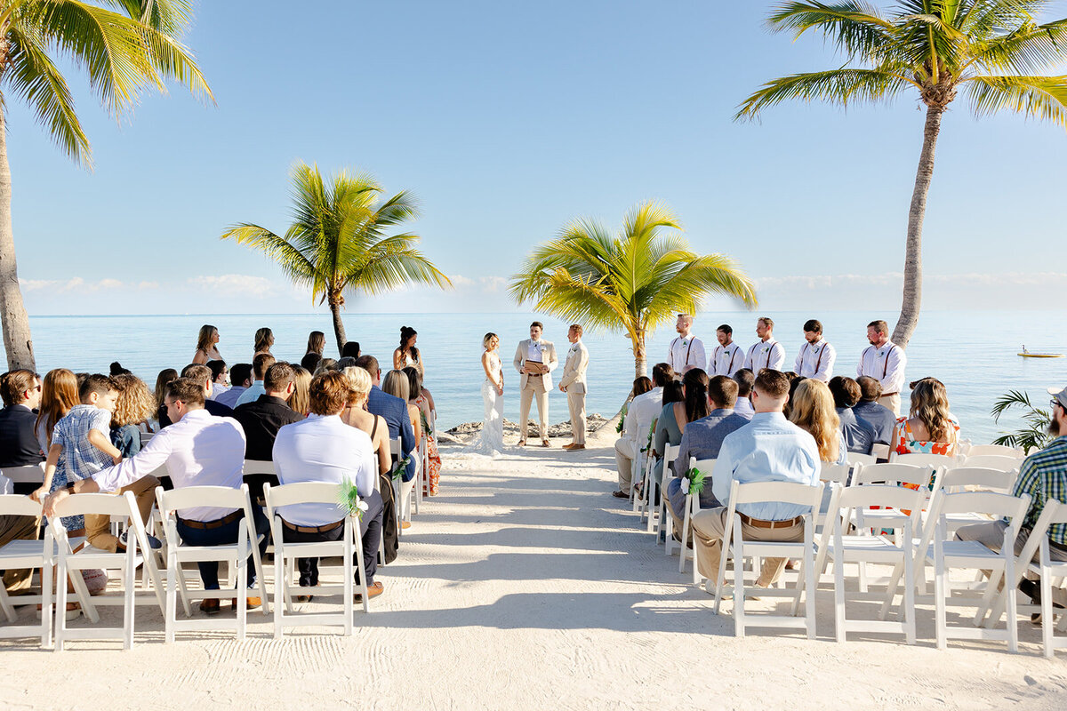 Wide shot of Ashley and Hunter smiling in the altar as they look into each other's eyes while the guests watch them.