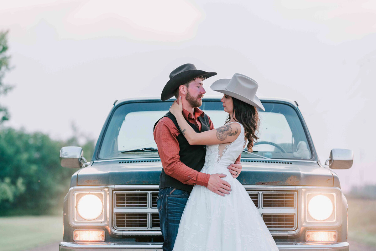 Bride and groom dance betwenn the headlights of the truck. 