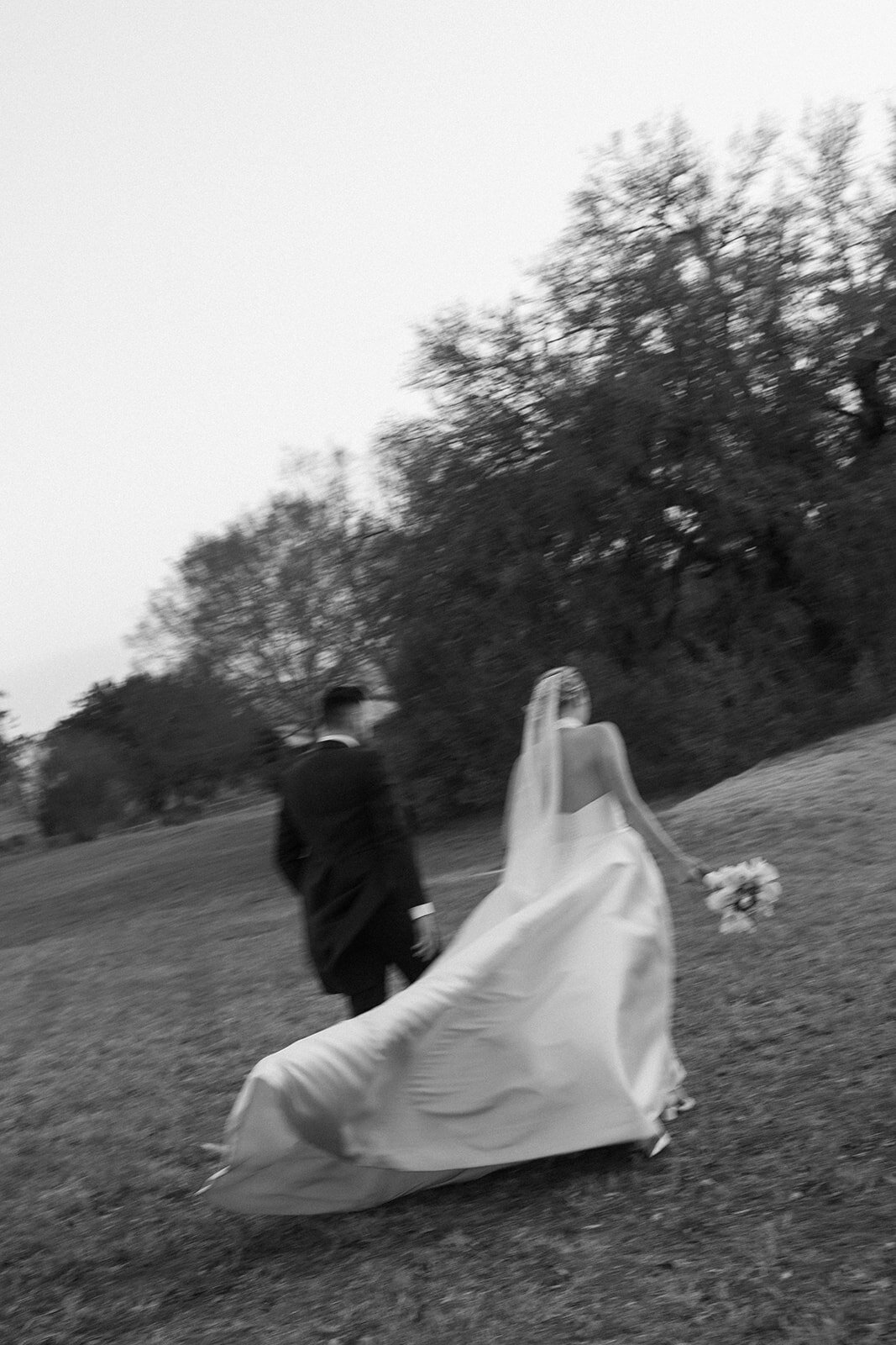 A bride and groom walking away from the camera to their reception.