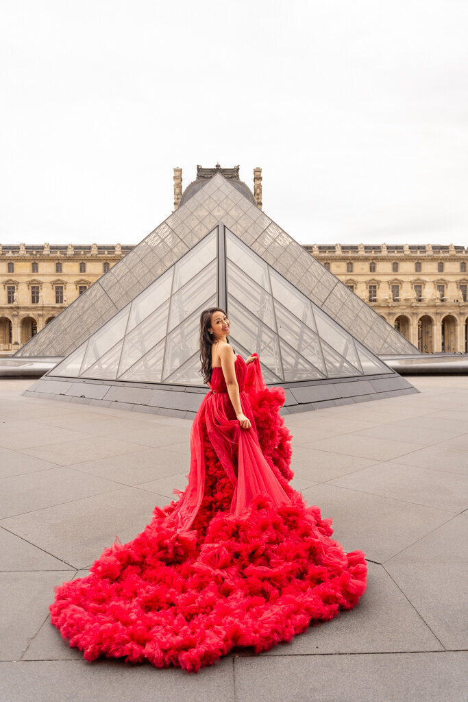 Princess portrait session at Louvre pyramid featuring Asian woman in red ball gown