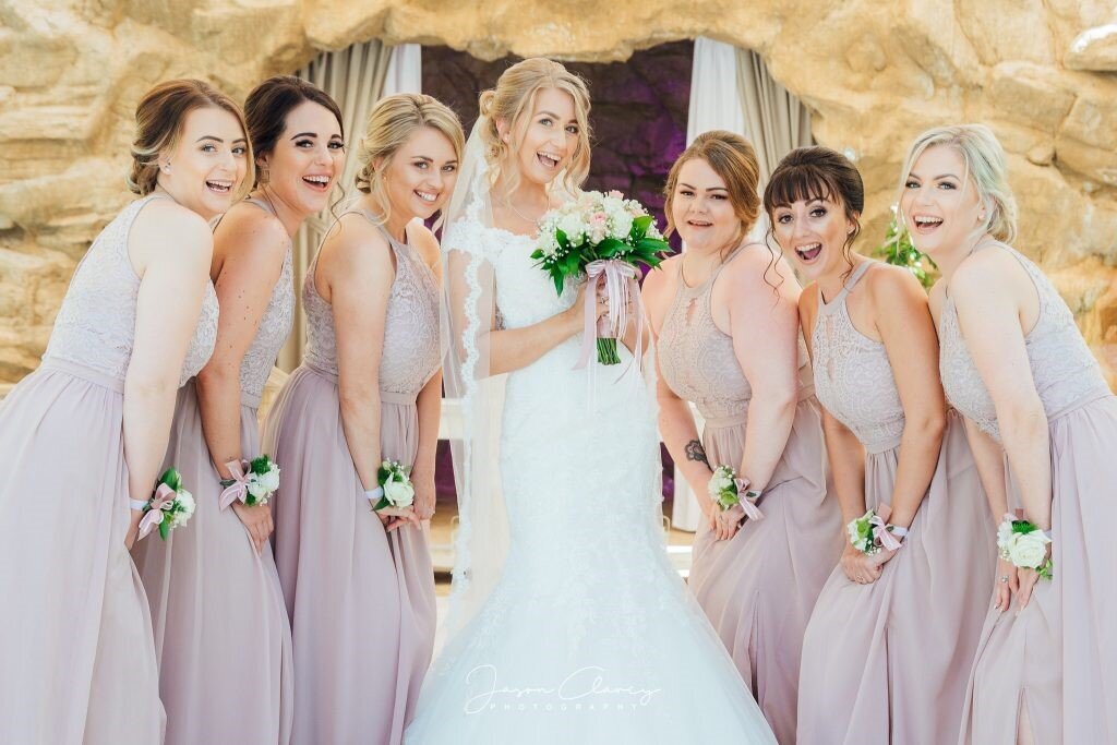 Bride with six bridesmaids smiling together after the ceremony