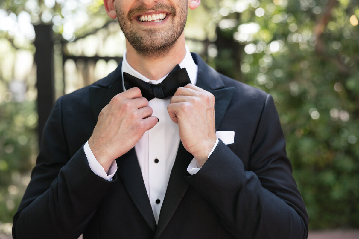 Closeup of groom adjusting bowtie at El Chorro in Paradise Valley, Arizona